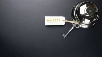 Avain, joka on kiinnitetty hotellin avaimenperään, jossa lukee ”M STAR HOTEL”, ja avain on asetettu tummalle alustalle.