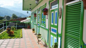 Un edifici amb parets exteriors de color verd i blanc, nombroses finestres i cistells de flors penjants.