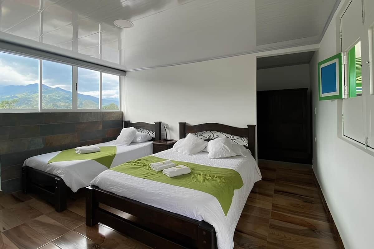 Ein Hotelzimmer mit zwei Betten, einem großen Fenster mit Blick auf die Berge und Holzböden.