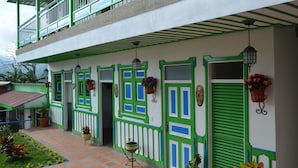 Un edifici de dues plantes amb parets exteriors verdes i blanques, diverses portes i fanals penjants.