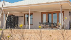 A modern house with a covered patio, large windows, and a dining area. - Stuart Range Outback Resort (Coober Pedy)