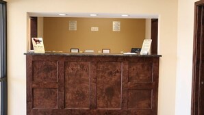 Una recepción con un panel de madera, un cartel de 'No se admiten mascotas' y una pizarra de menú.
