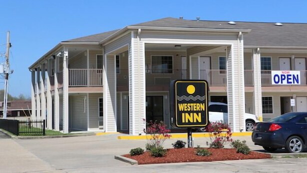 Edificio del Western Inn con un porche cubierto, varios balcones y un cartel que indica que está abierto.
