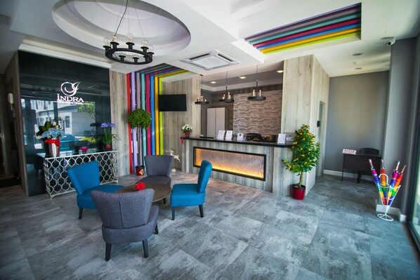 Un moderno vestíbulo de hotel con mostrador de recepción, zona de estar y una pared con rayas de colores.
