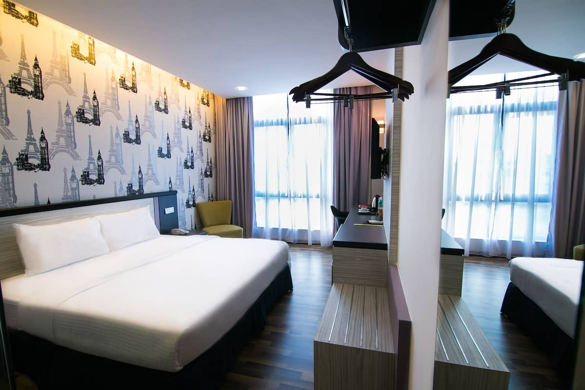 Une chambre d’hôtel avec un grand lit, un bureau, une chaise et une armoire.