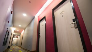 Pasillo de hotel con puertas numeradas 21 y 22, pisos alfombrados e iluminación empotrada en el techo.