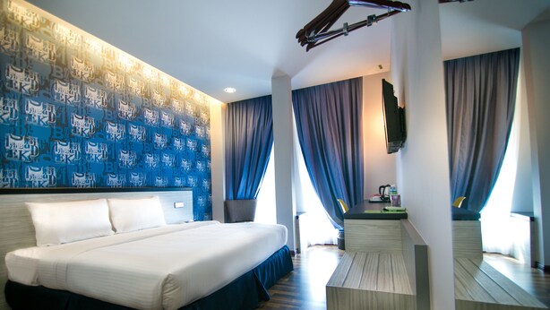 Habitación de hotel con una cama grande, un televisor de pantalla plana en la pared y suelo de madera.