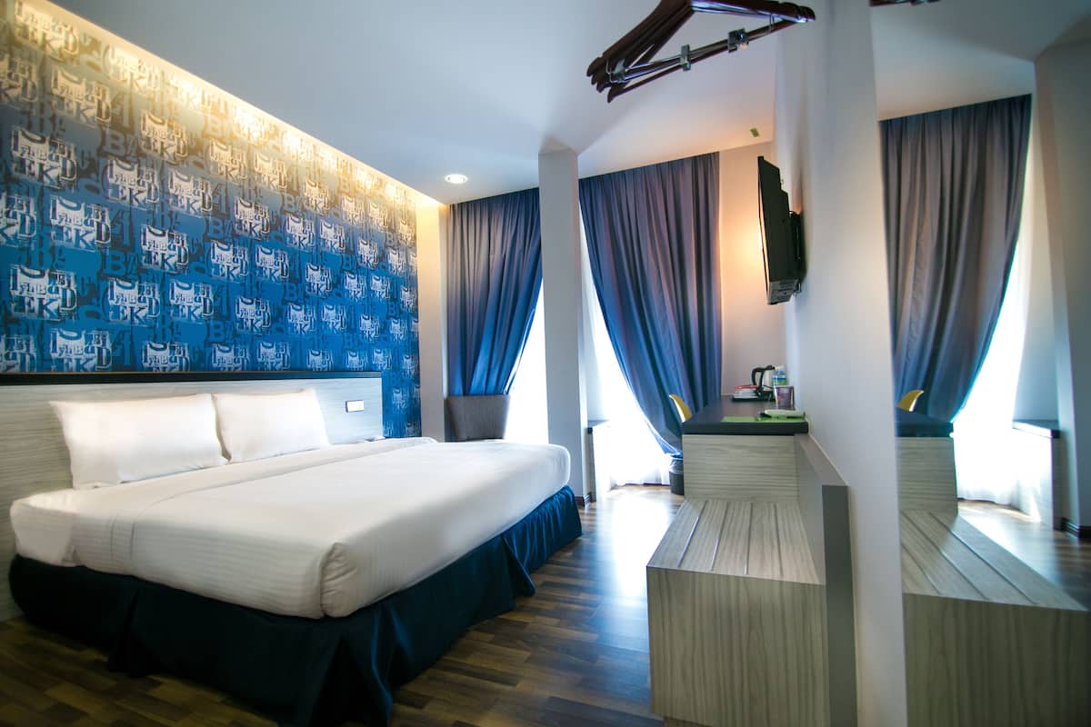 Une chambre d’hôtel avec un grand lit, un téléviseur à écran plat fixé au mur et un plancher en bois.
