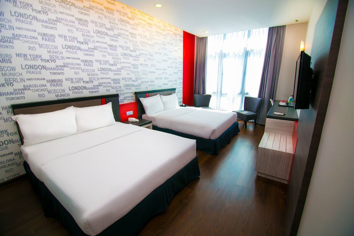 Une chambre d’hôtel avec deux lits, un bureau, une chaise et un téléviseur.