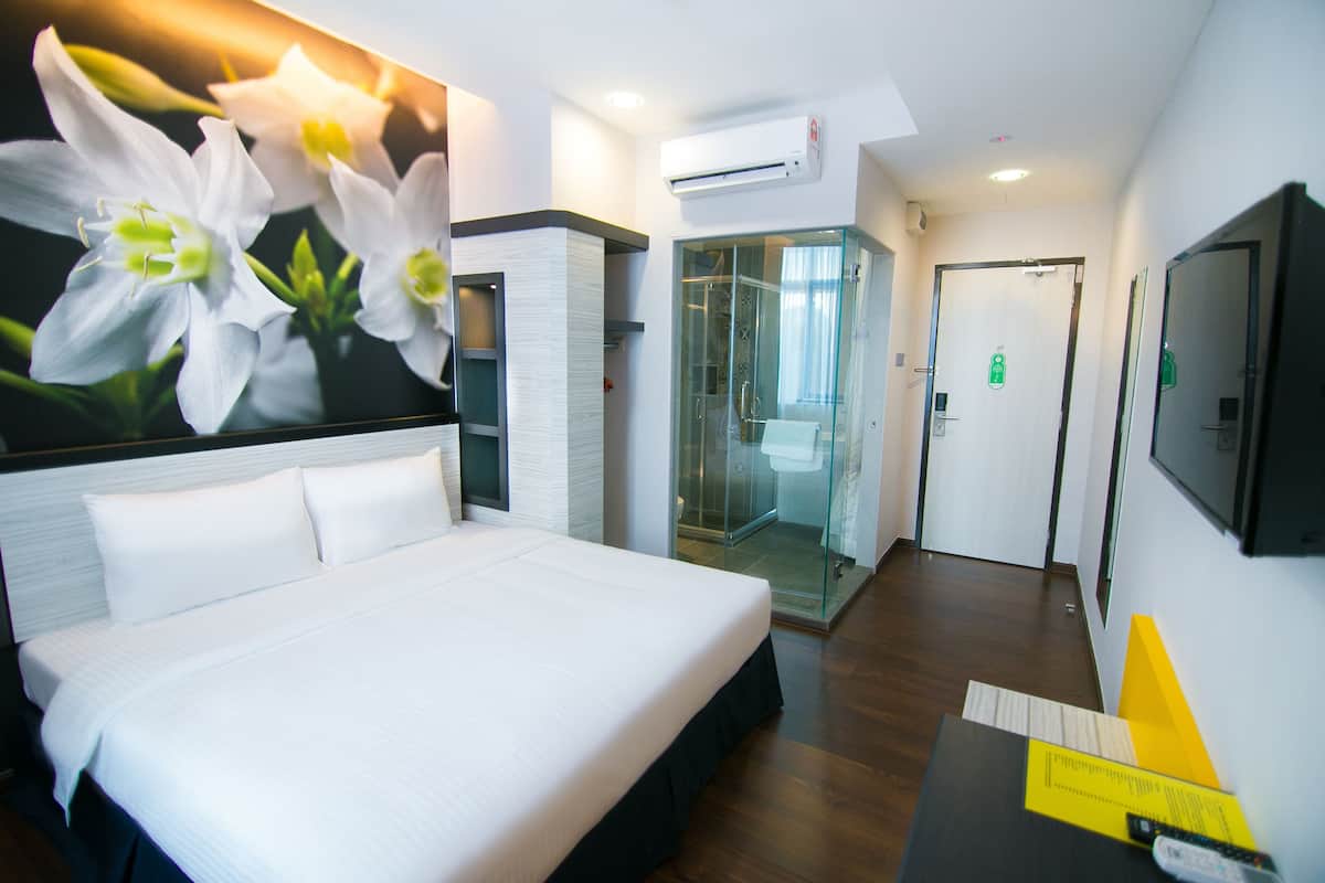 Une chambre d’hôtel dotée d’un grand lit, d’une douche en verre, d’un téléviseur fixé au mur et d’un climatiseur mural.