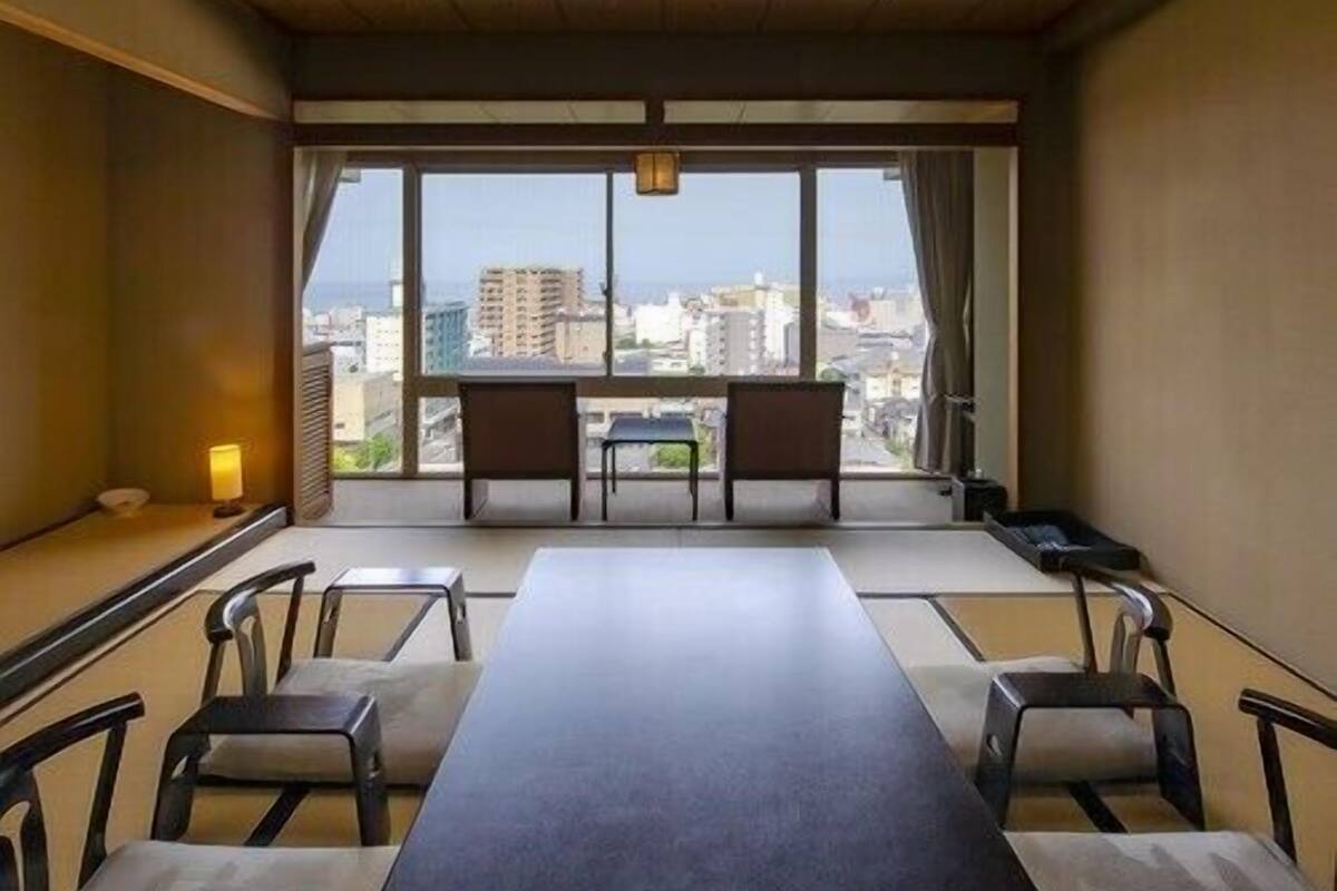 A conference room with a long table, chairs, a view of the city, and a traditional ceiling design.