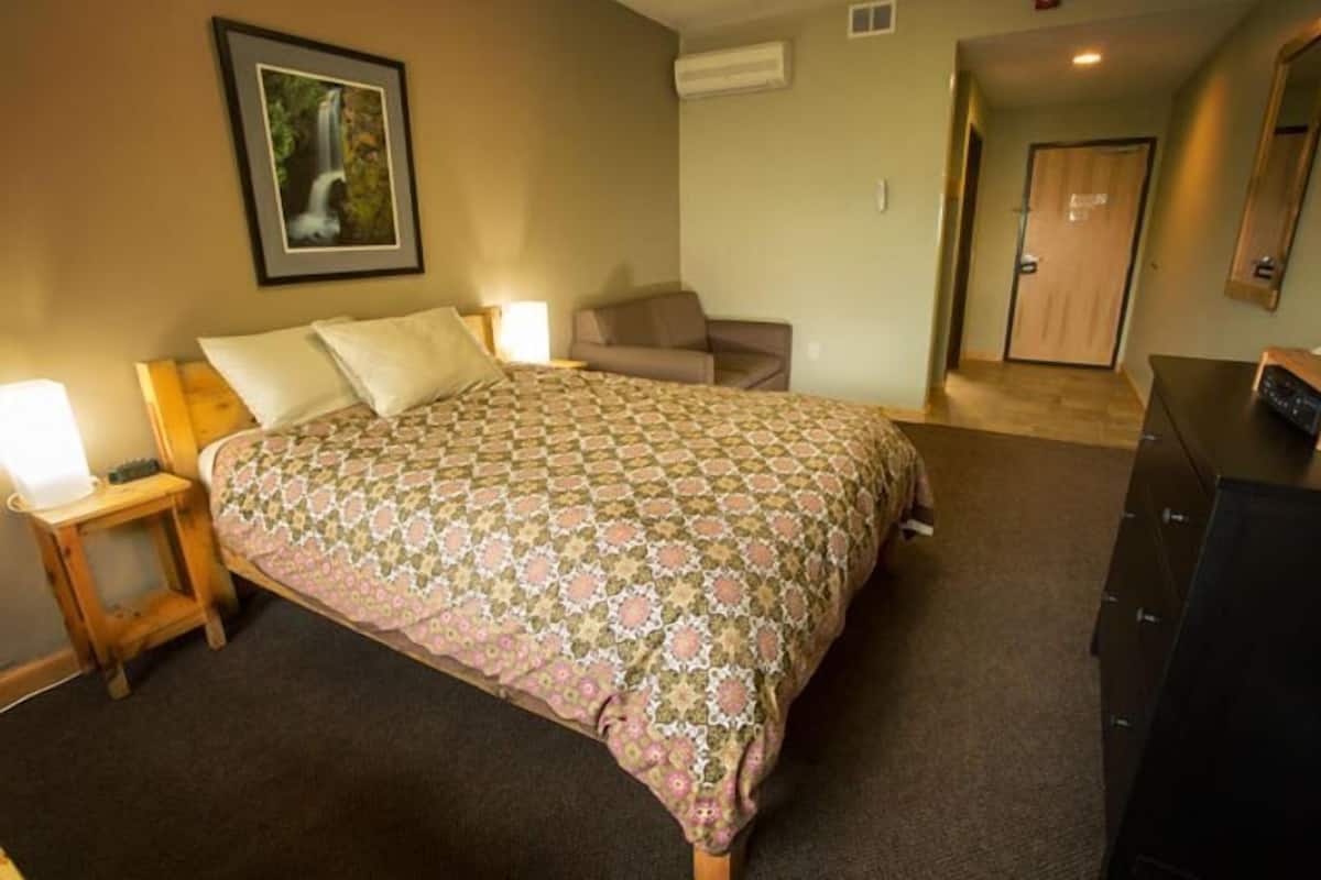 Ein Schlafzimmer mit Bett, Nachttisch, Kommode, Sofa und Tür.