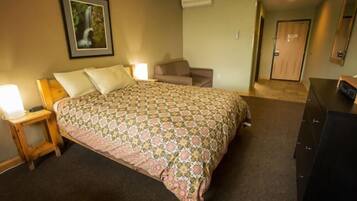 A bedroom with a bed, a nightstand, a dresser, a couch, and a door.