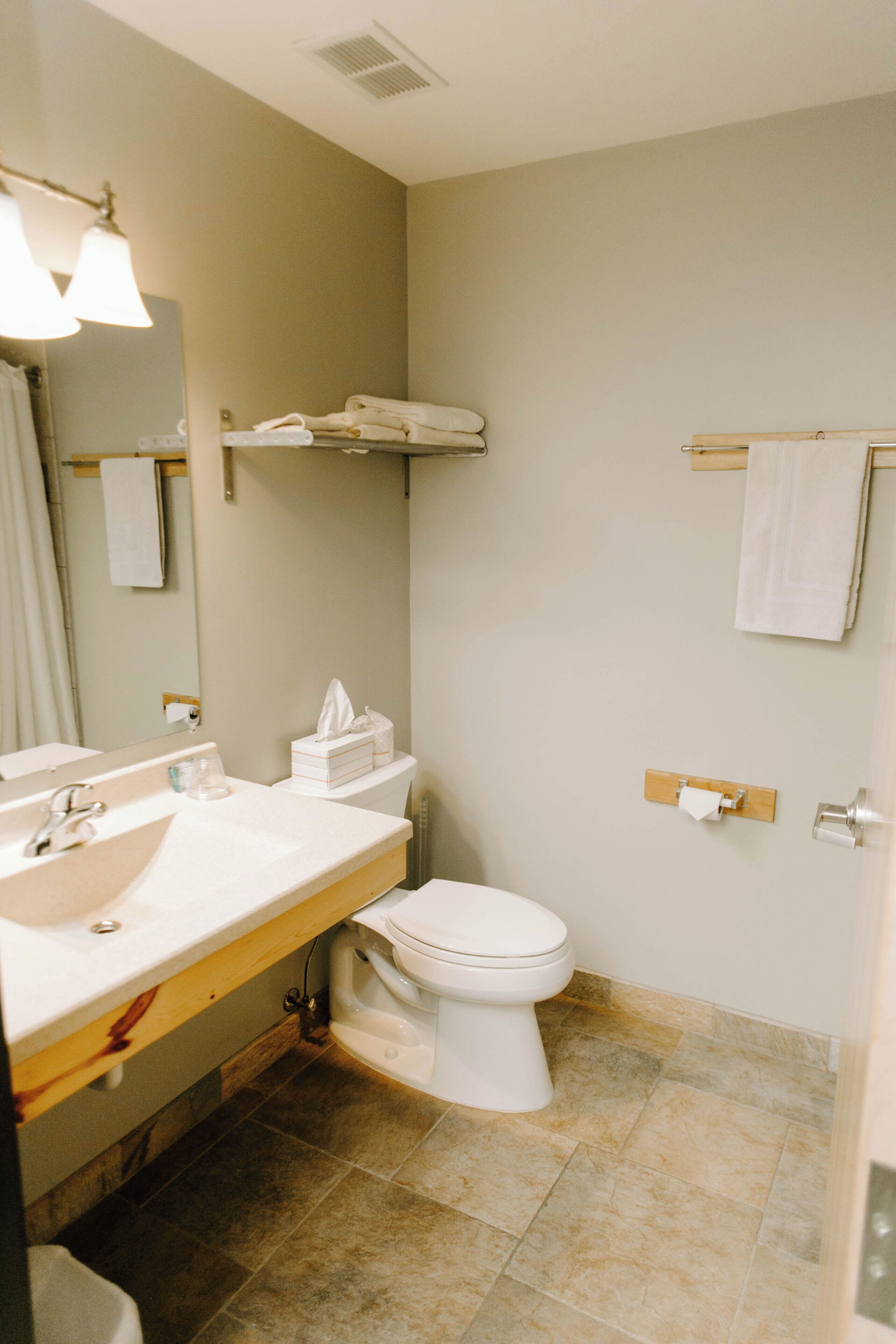 A bathroom with a sink, mirror, toilet, and towel rack.