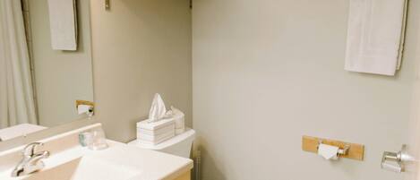 A bathroom with a sink, mirror, toilet, and towel rack.