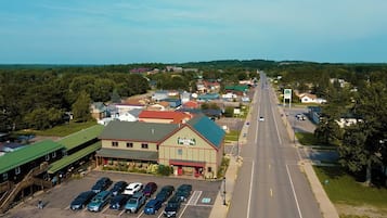 An aerial view of a town with a prominent building labeled "Adventure Inn" in the foreground, featuring a parking lot with several cars.