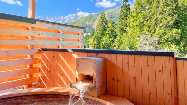 A wooden sauna with a wooden bench and a small wooden structure with water flowing into a basin. - Bergtour Marukita (Hakuba)