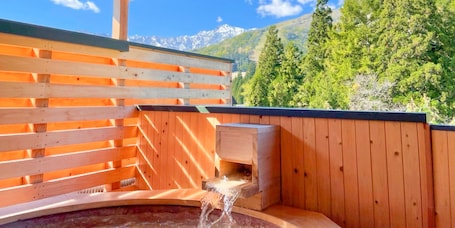 A wooden sauna with a wooden bench and a small wooden structure with water flowing into a basin.
