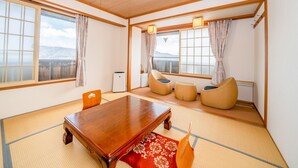 A traditional Japanese room with tatami flooring, a wooden table, and a view of the mountains. - Bergtour Marukita (Hakuba)