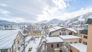 A snow-covered town with buildings and a mountain in the background. - Bergtour Marukita (Hakuba)