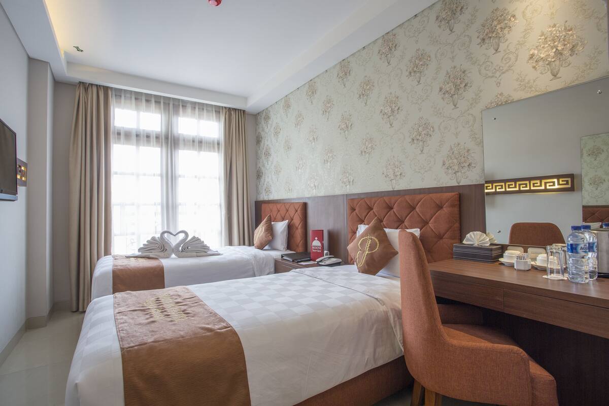 Une chambre d’hôtel avec deux lits, un bureau et un miroir.