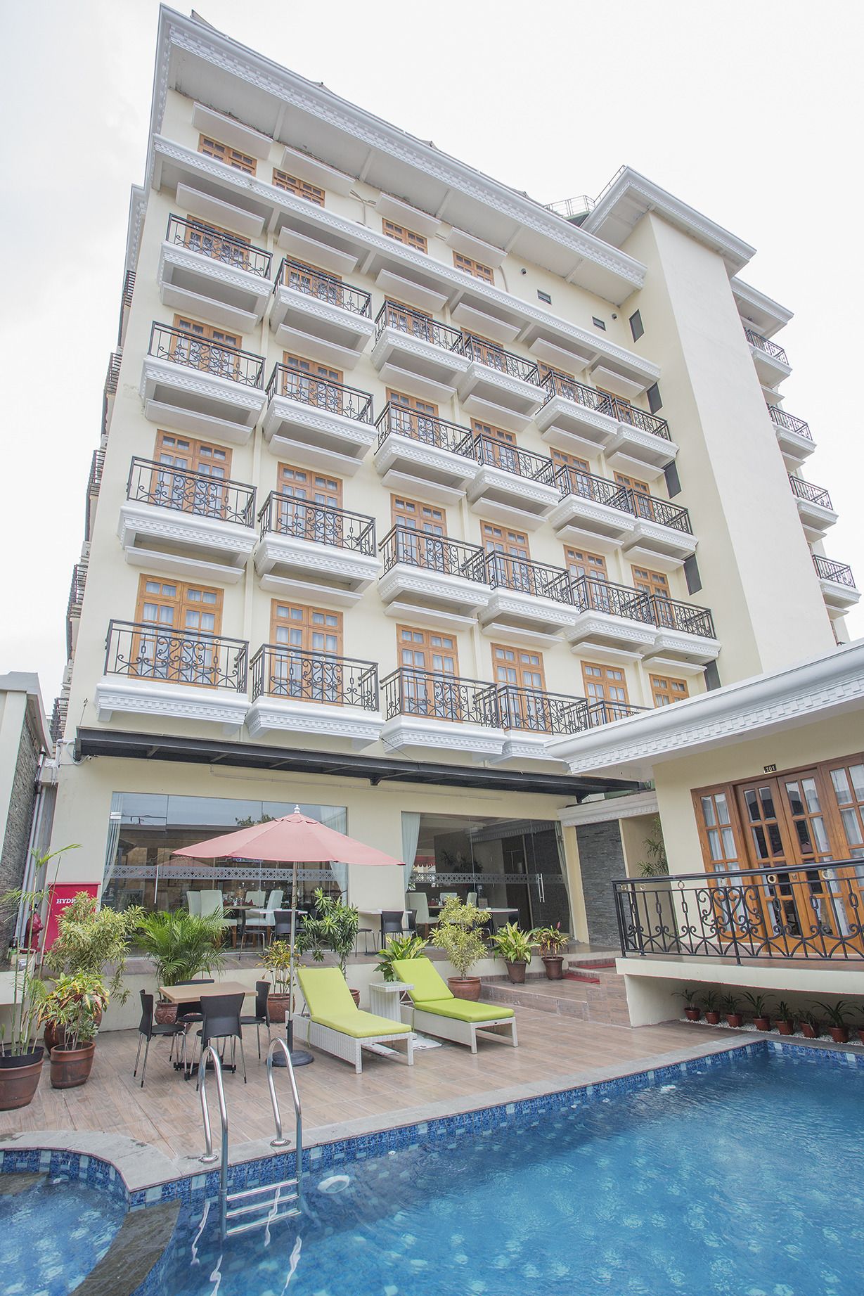 Un hôtel à plusieurs étages doté d’une piscine, d’un espace extérieur aménagé et de balcons.