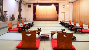 Una habitación japonesa tradicional con esteras de tatami, muebles de madera y cojines rojos.