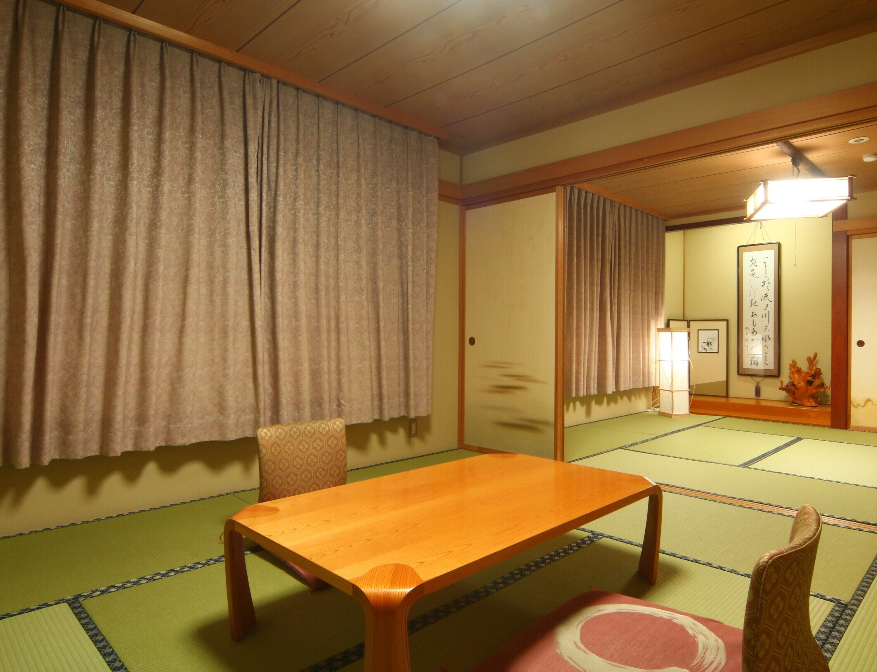 A traditional Japanese room with tatami flooring, a wooden table, a chair, and sliding doors.