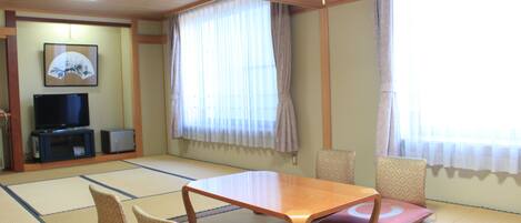 A traditional Japanese room with tatami flooring, a low wooden table, and cushions.