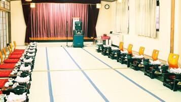 A conference room with rows of chairs, a podium, and a stage with curtains.