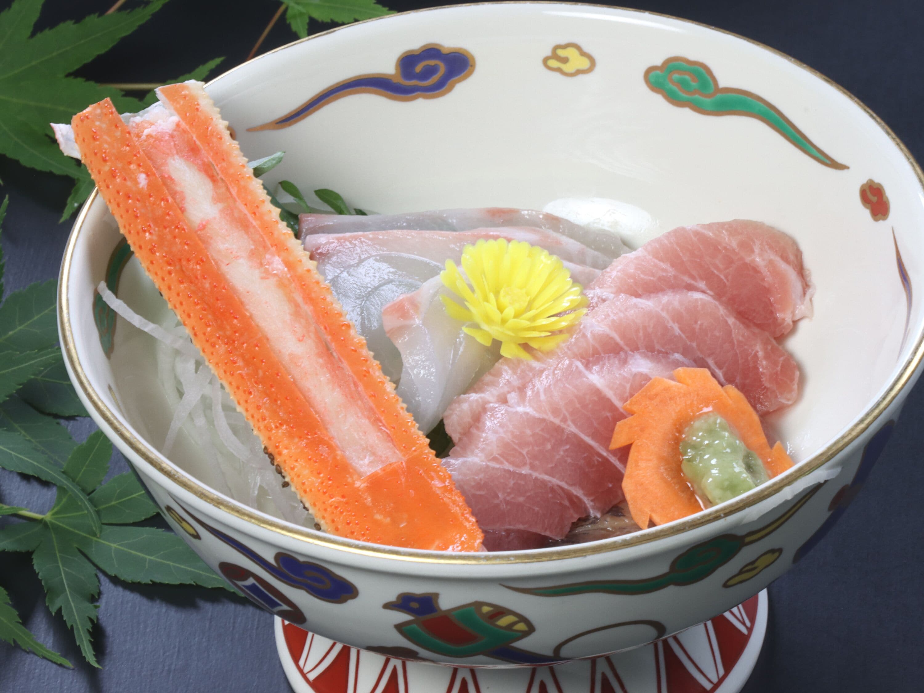 A bowl of sashimi with various fish slices and a decorative flower.