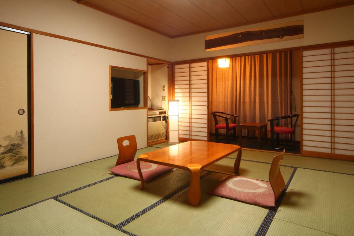 A traditional Japanese room with tatami flooring, a wooden table, and shoji screens.