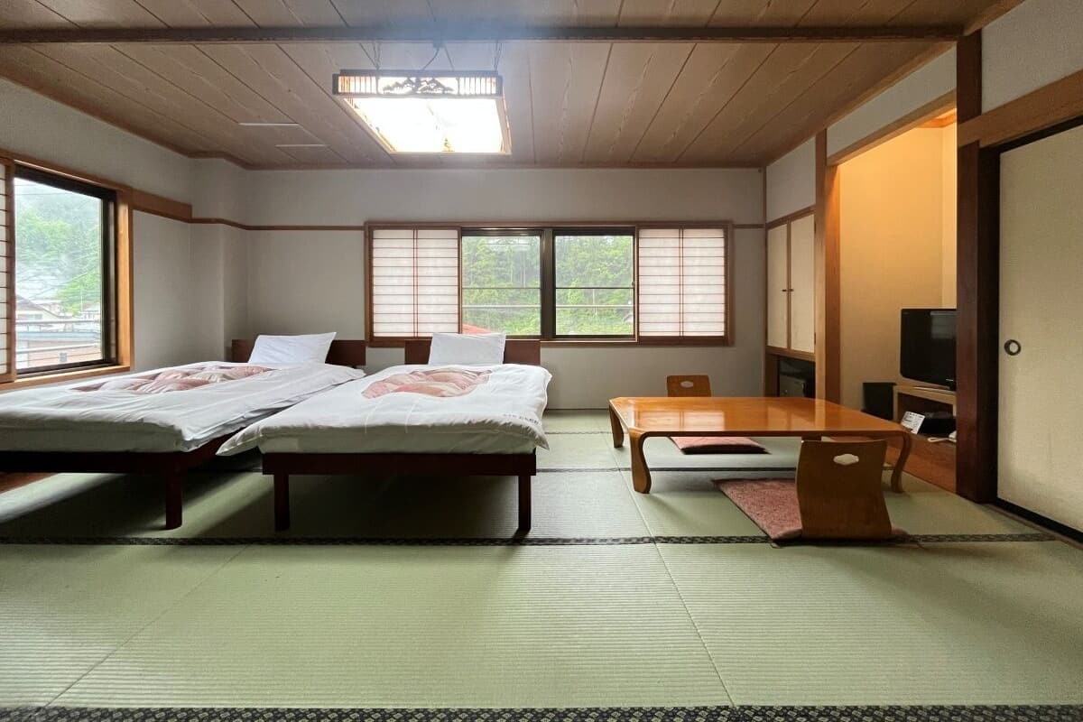 A traditional Japanese room with tatami flooring, a low wooden ceiling, and sliding doors.