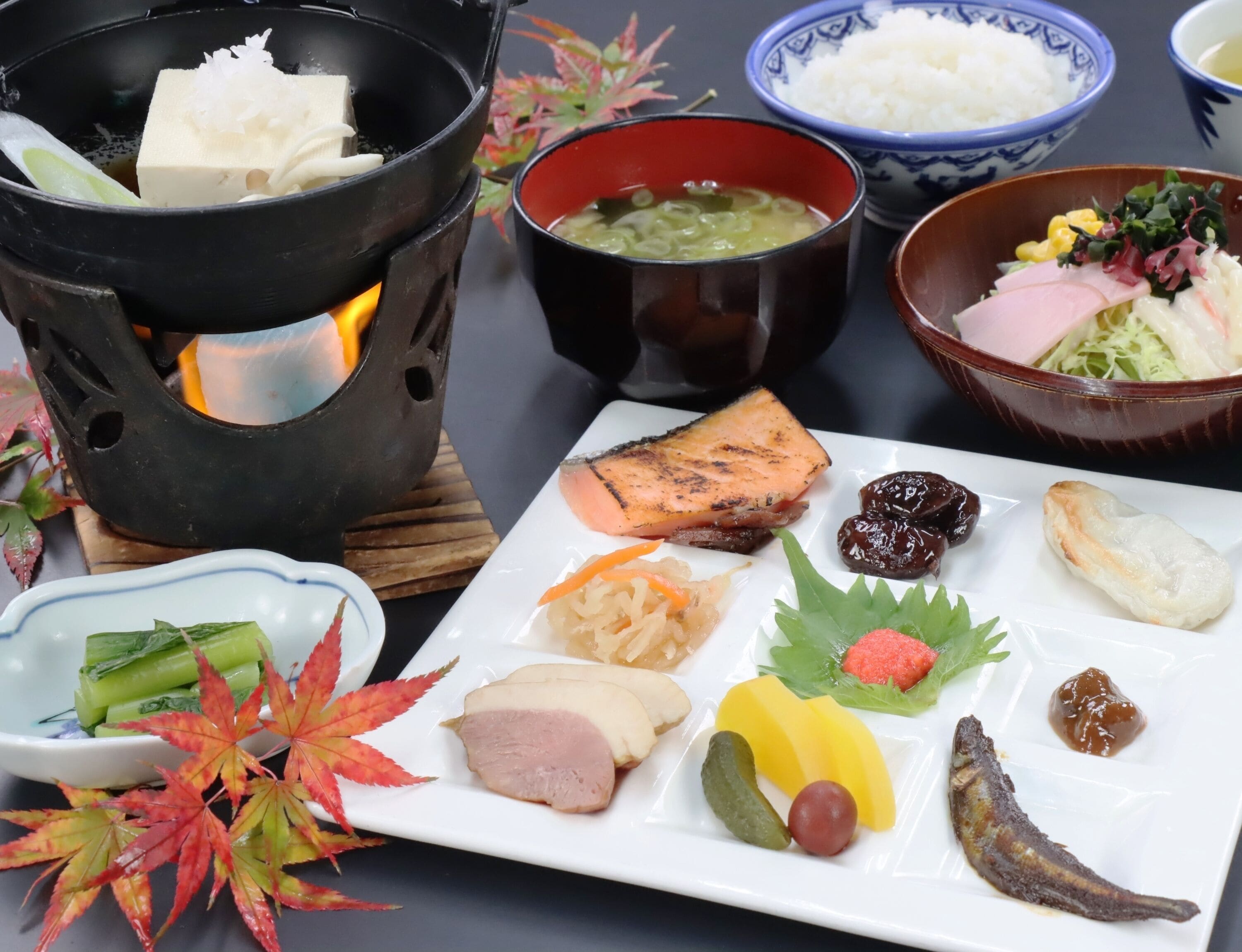 Una comida tradicional japonesa con diversos platos, incluyendo pescado, verduras y encurtidos.