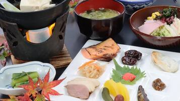 Una comida tradicional japonesa con diversos platos, incluyendo pescado, verduras y encurtidos.