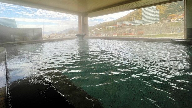 Una piscina interior con agua cristalina, vista a un paisaje urbano y techo de madera.