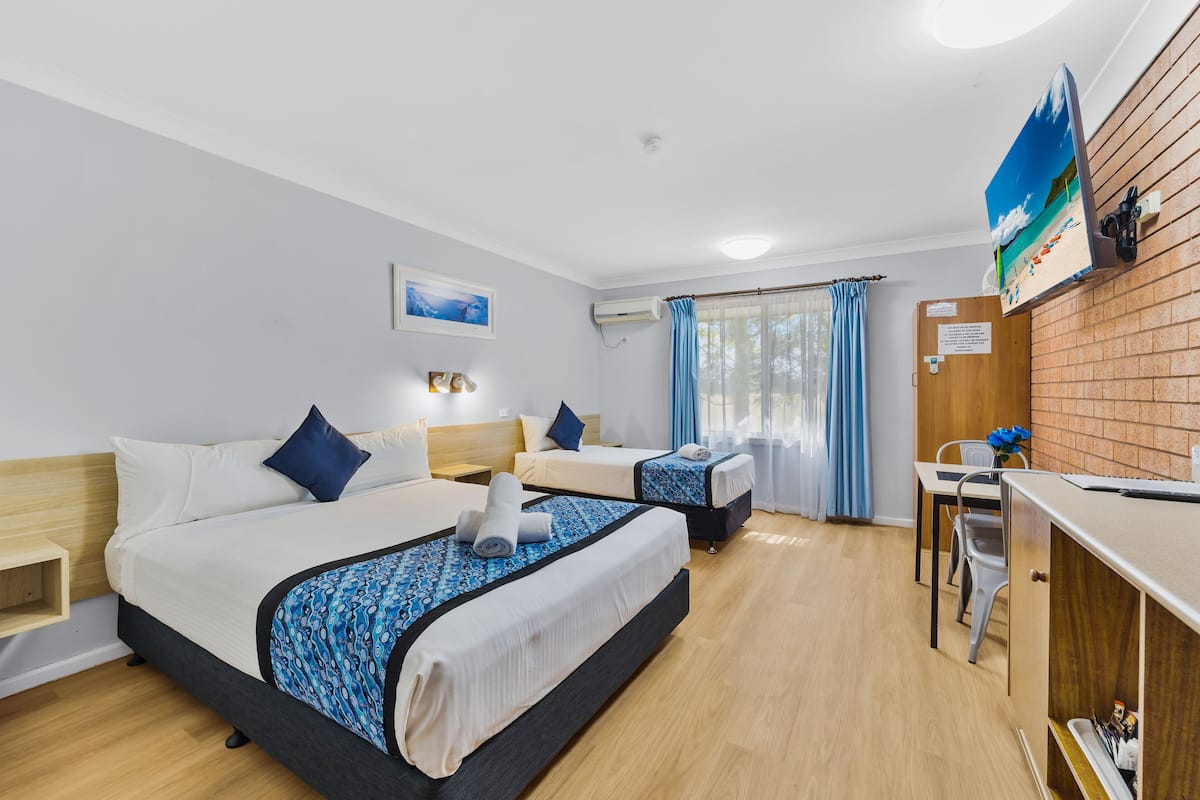 A hotel room with two beds, a desk, and a chair.