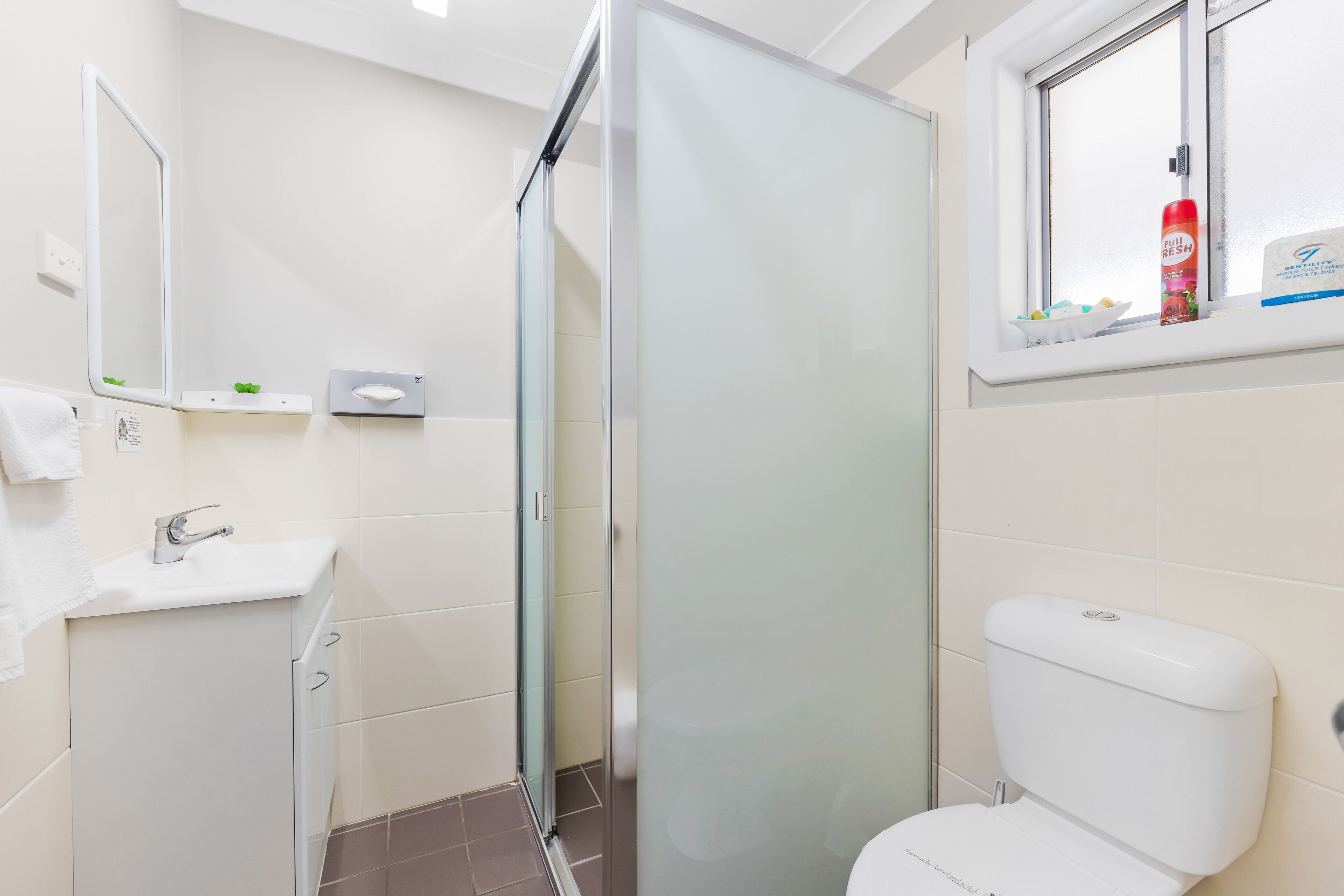 A modern bathroom with a glass shower enclosure, a white sink, and a toilet.