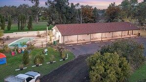 Una casa grande con un patio cubierto, una piscina y un patio cercado.