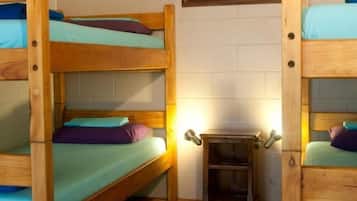 A room with two bunk beds, a small wooden table, and a framed picture on the wall.