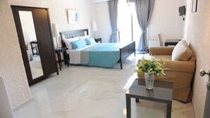 A hotel room with a bed, a sofa, a coffee table with a vase, and a door. - Valentino Hotel (Rhodes)