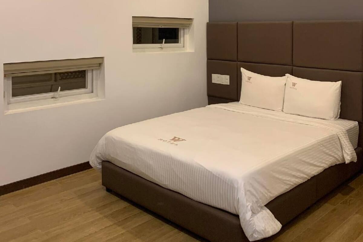 Een moderne slaapkamer met een groot bed, hoofdeinde en een klein raam.