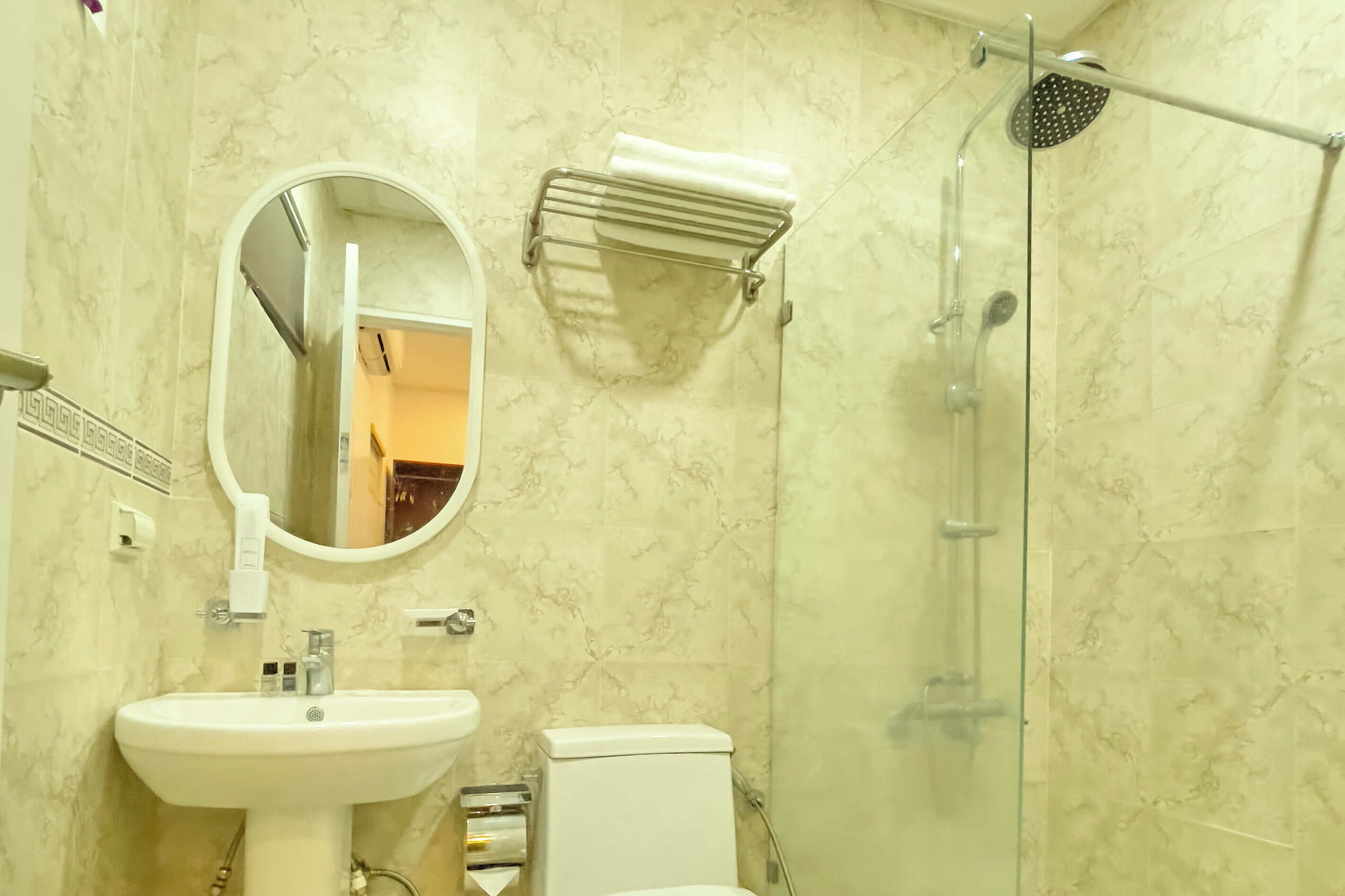 A bathroom with a sink, toilet, mirror, and shower.