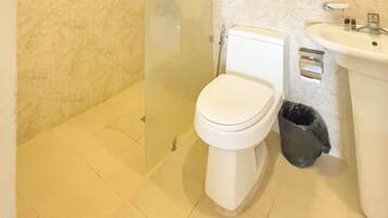 A bathroom with a toilet, sink, and trash bin.