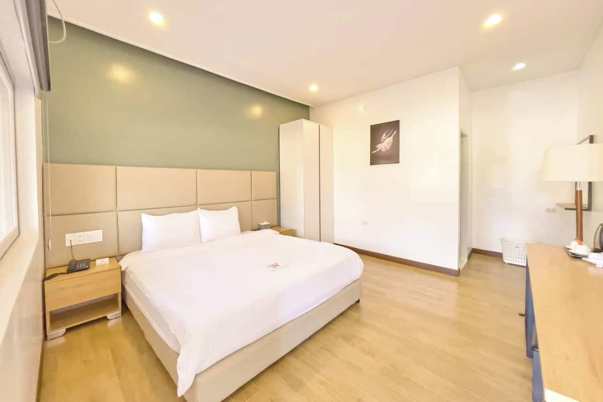 Een hotelkamer met een bed, nachtkastje, kast en bureau met lamp.