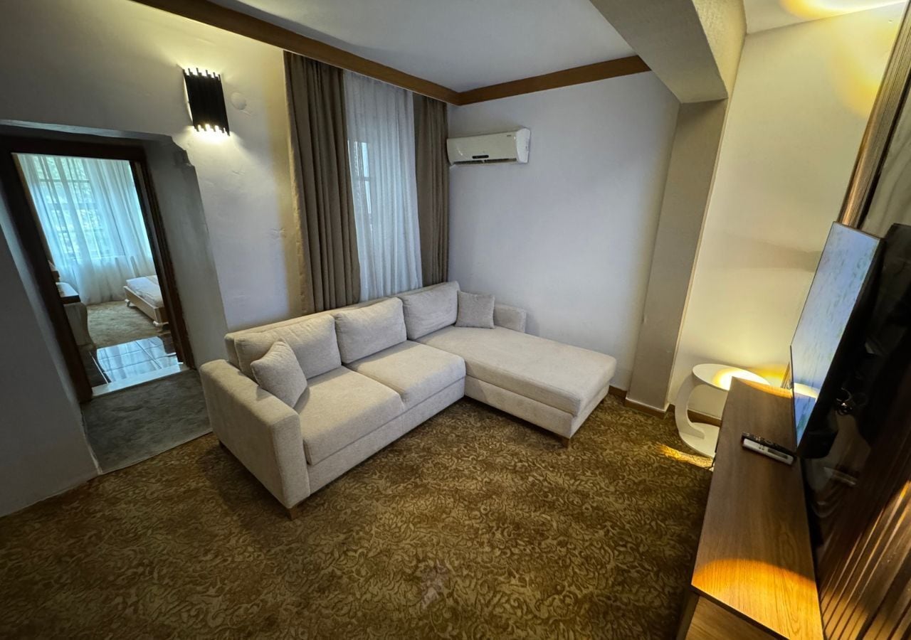 Habitación de hotel moderna con sofá modular, televisión de pantalla plana, equipo de aire acondicionado y alfombra estampada.