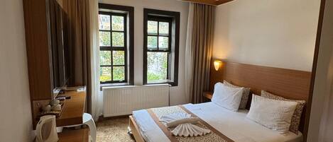 Une chambre d’hôtel avec un lit, une table de chevet, une lampe et une fenêtre avec des rideaux.