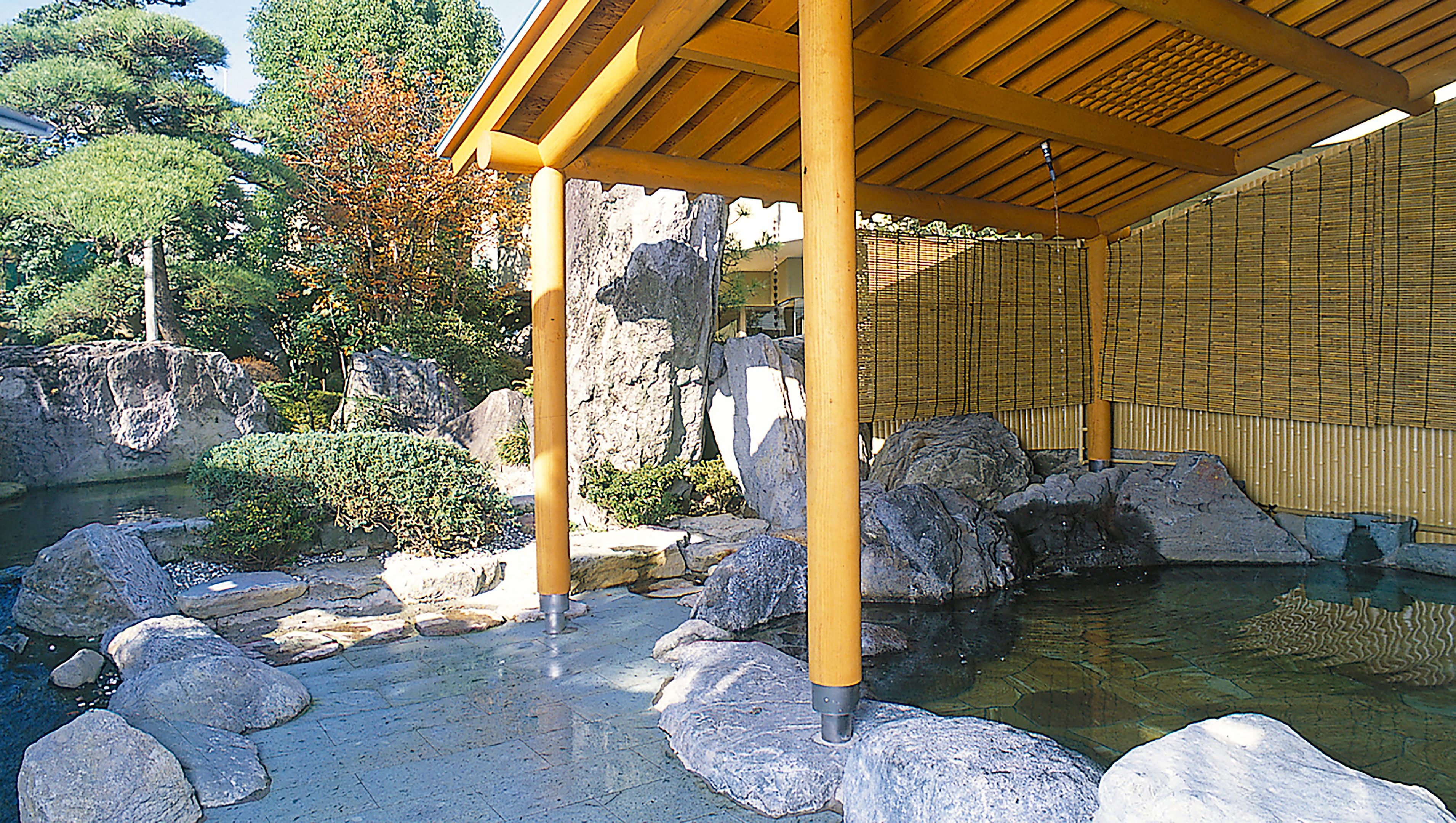 Ein traditioneller japanischer Garten mit einem hölzernen Pavillon, einem Teich mit Koi-Karpfen und großen Felsen.