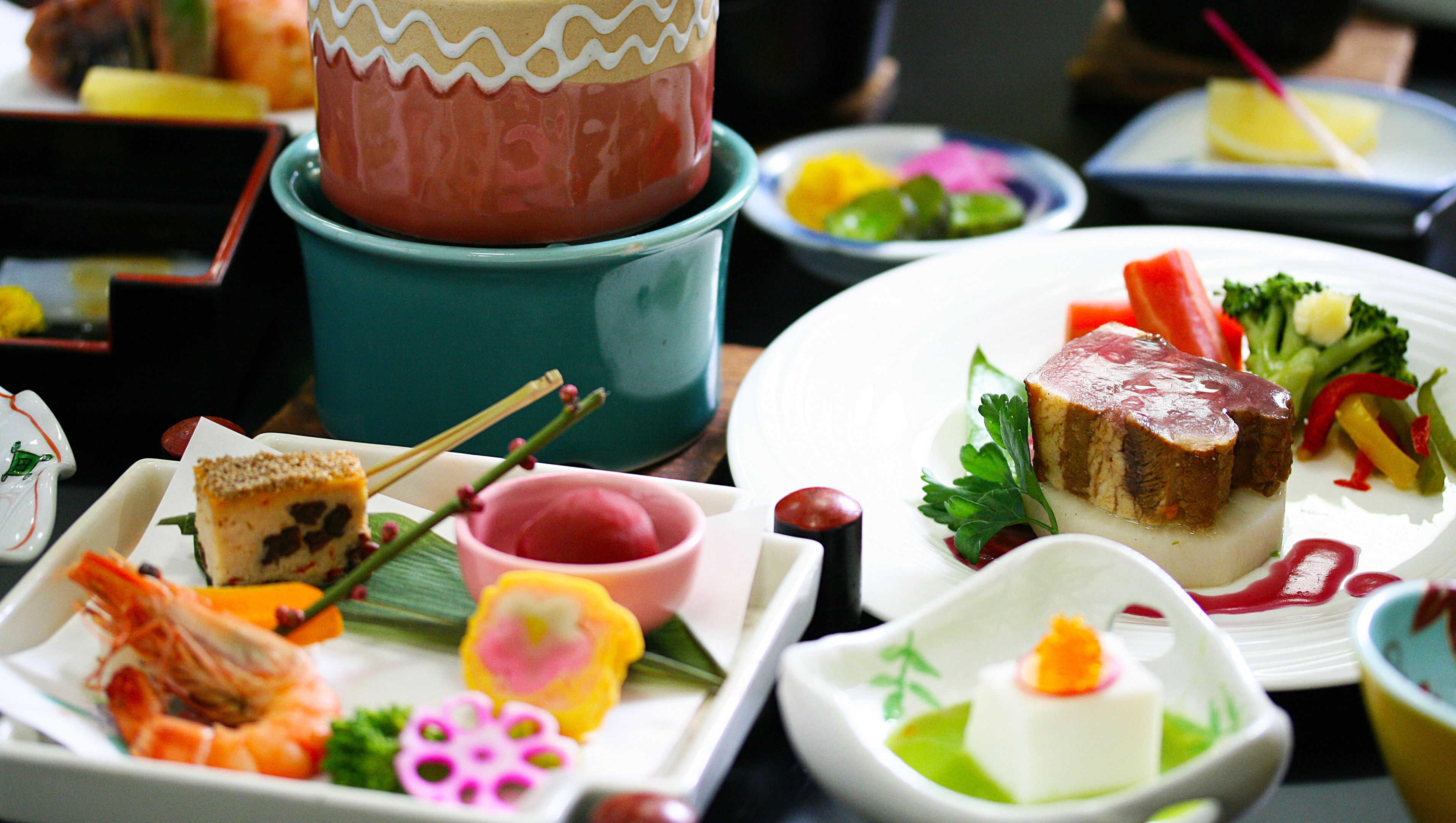 A variety of dishes on a table, including sushi, sashimi, and a cake with a decorative top.