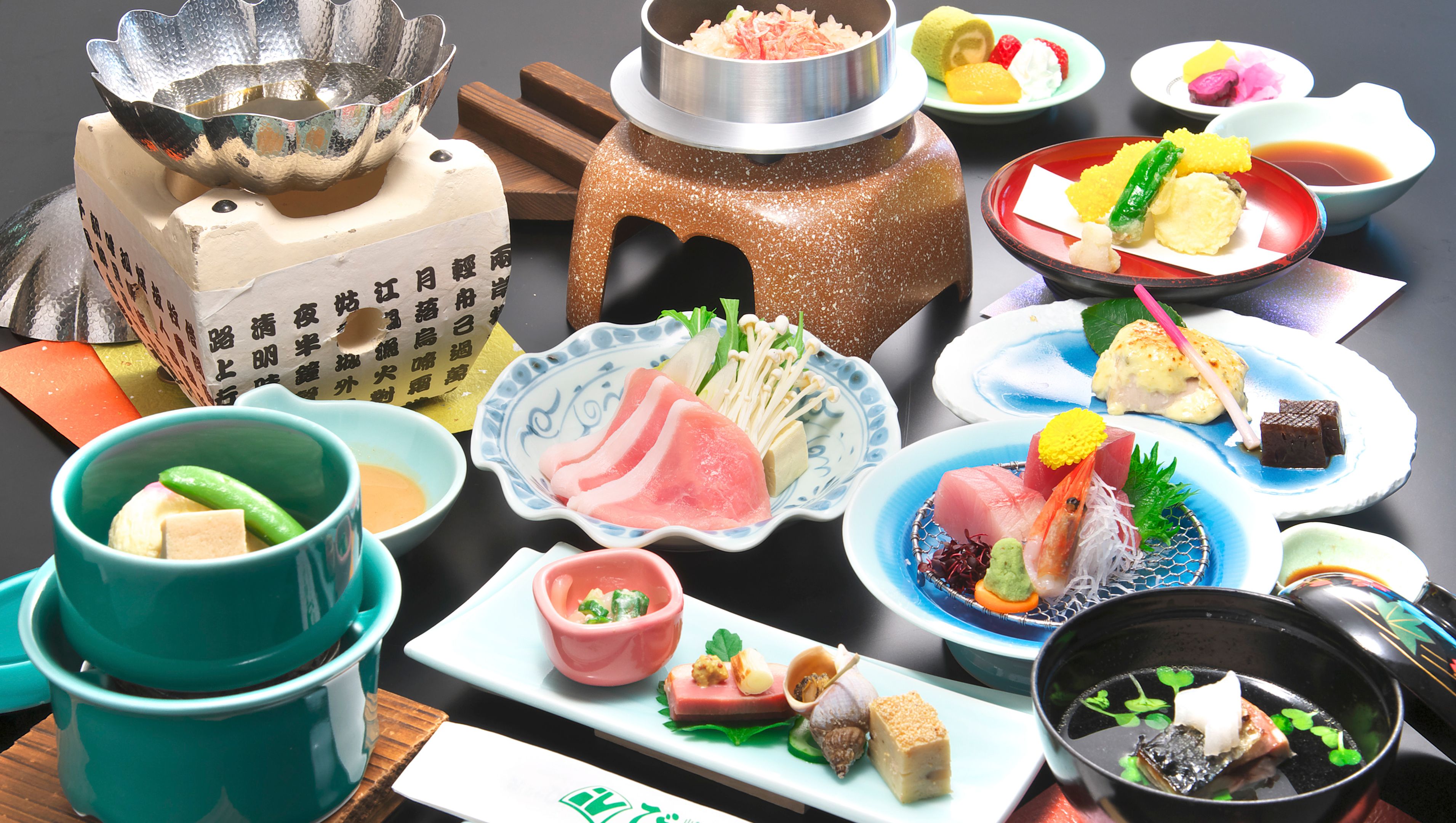 A variety of Japanese dishes including sushi, sashimi, and tempura, served on a table with multiple bowls and plates.